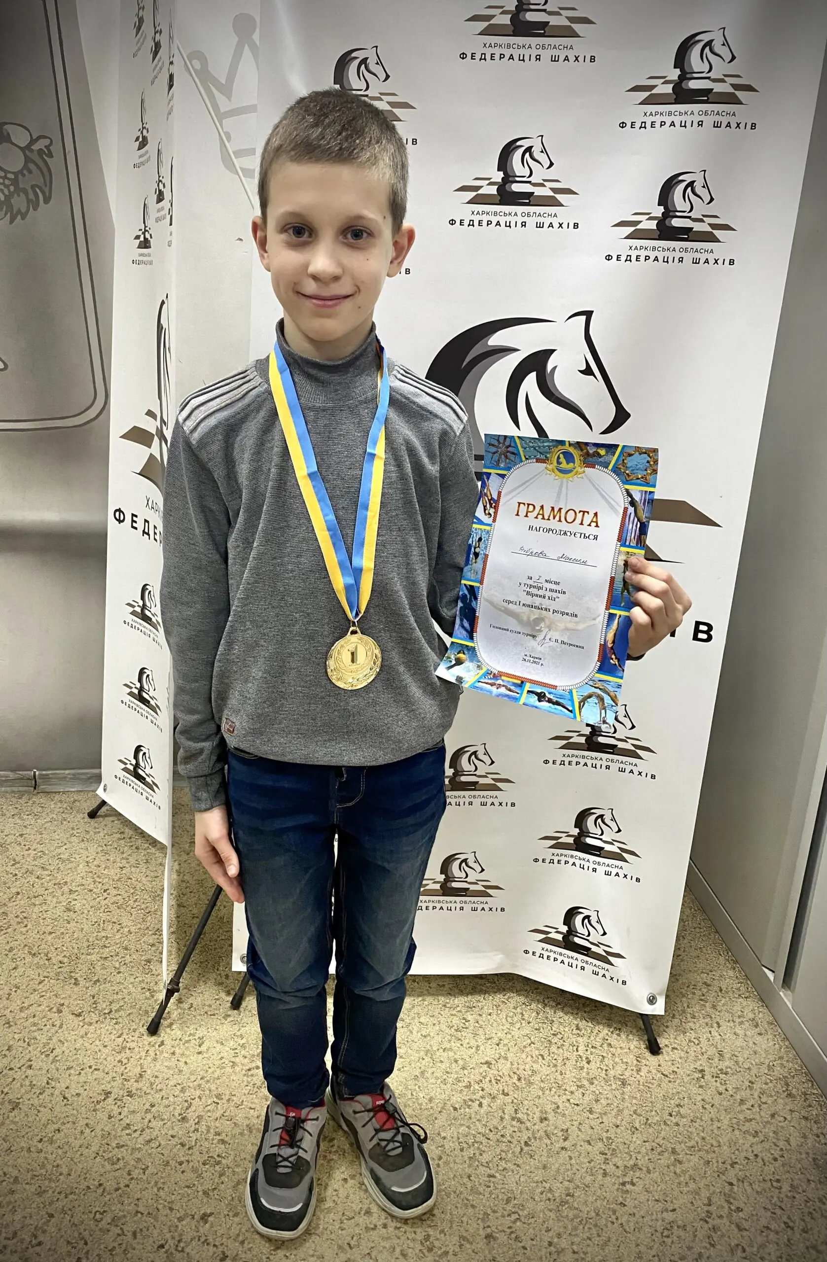 Sjakkspiller Maksym med diplom og gullmedalje i snor med ukrainske farger