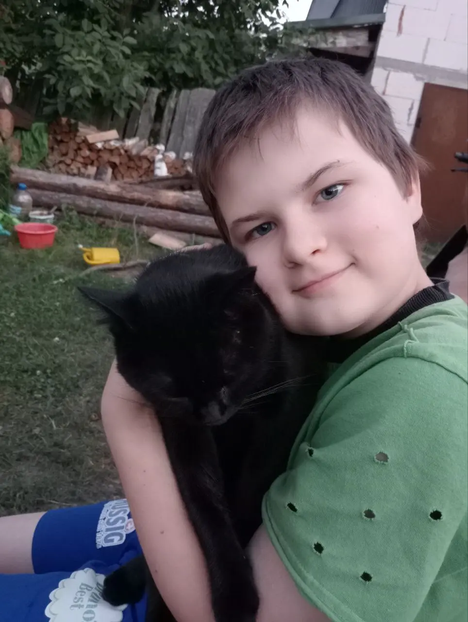 Gutt i grønn genser koser med svart katt, bilde tatt i Ukraina